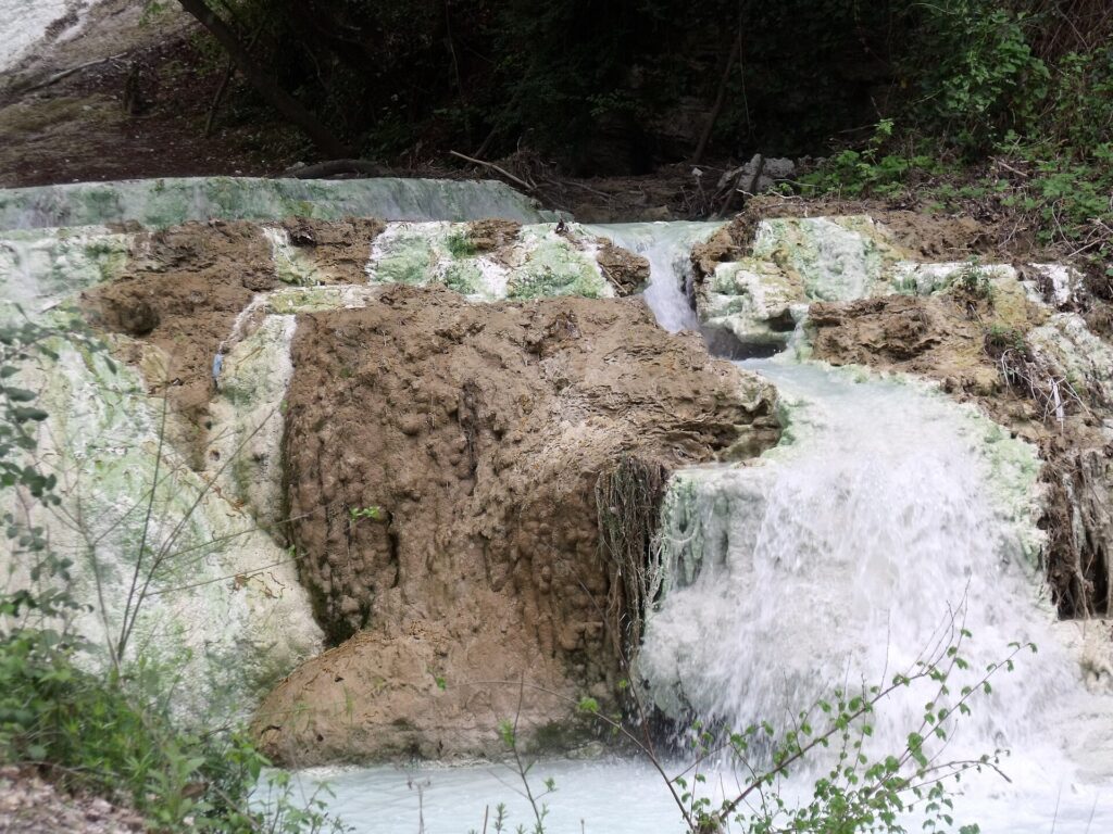 Hot water cascading over white limestone deposits in the Fosso Bianco stream at Bagni San Filippo