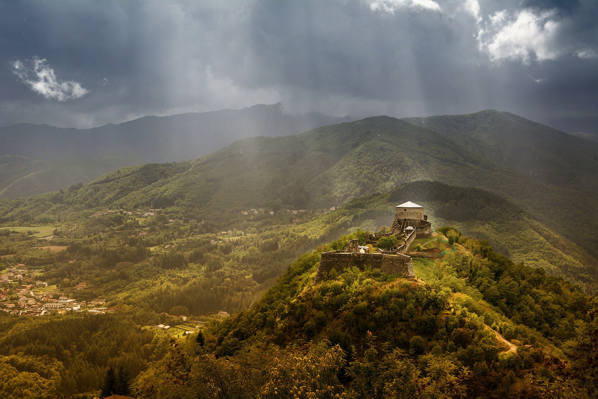 Sunbeams lighting the Fortezza delle Verrucole on its wooded hilltop above the Garfagnana valley