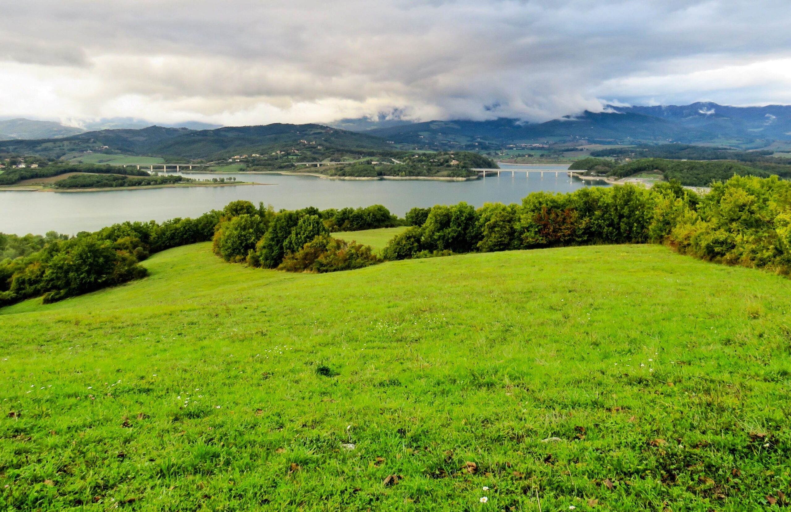 Lake Bilancino in the Mugello with green meadows in front and the Tuscan-Emilian Apennines behind