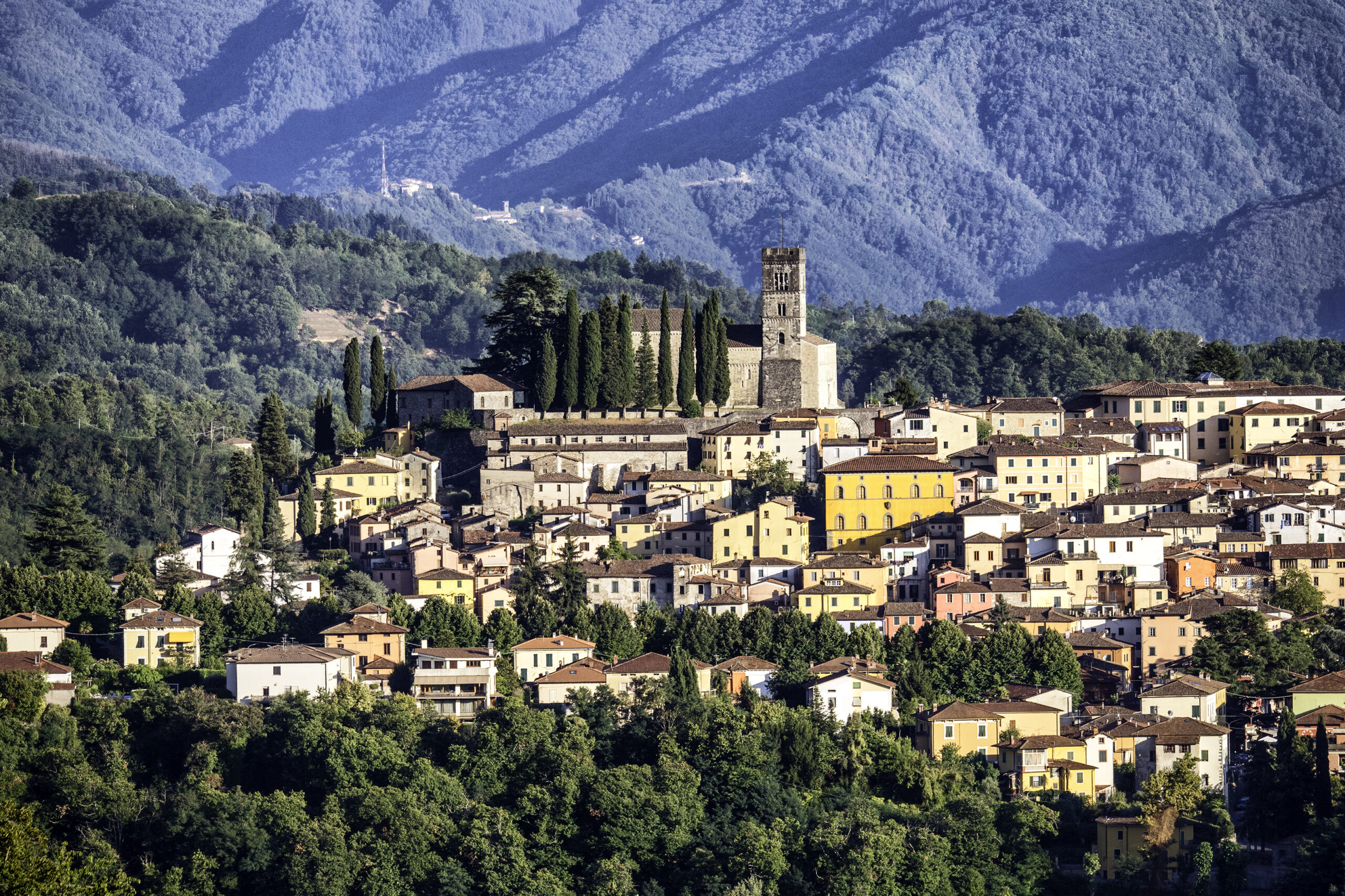 Barga's hillside old town of ochre and terracotta houses crowned by the Duomo bell tower, mountains behind