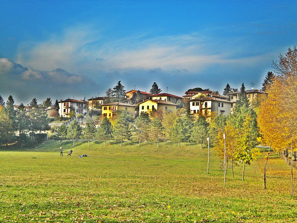 Vicchio in the Mugello, its houses on the ridge above autumn-coloured trees and a green meadow